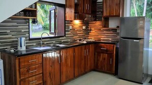 Una cocina con armarios de madera, un refrigerador de acero inoxidable y una ventana con vista a un jardín.