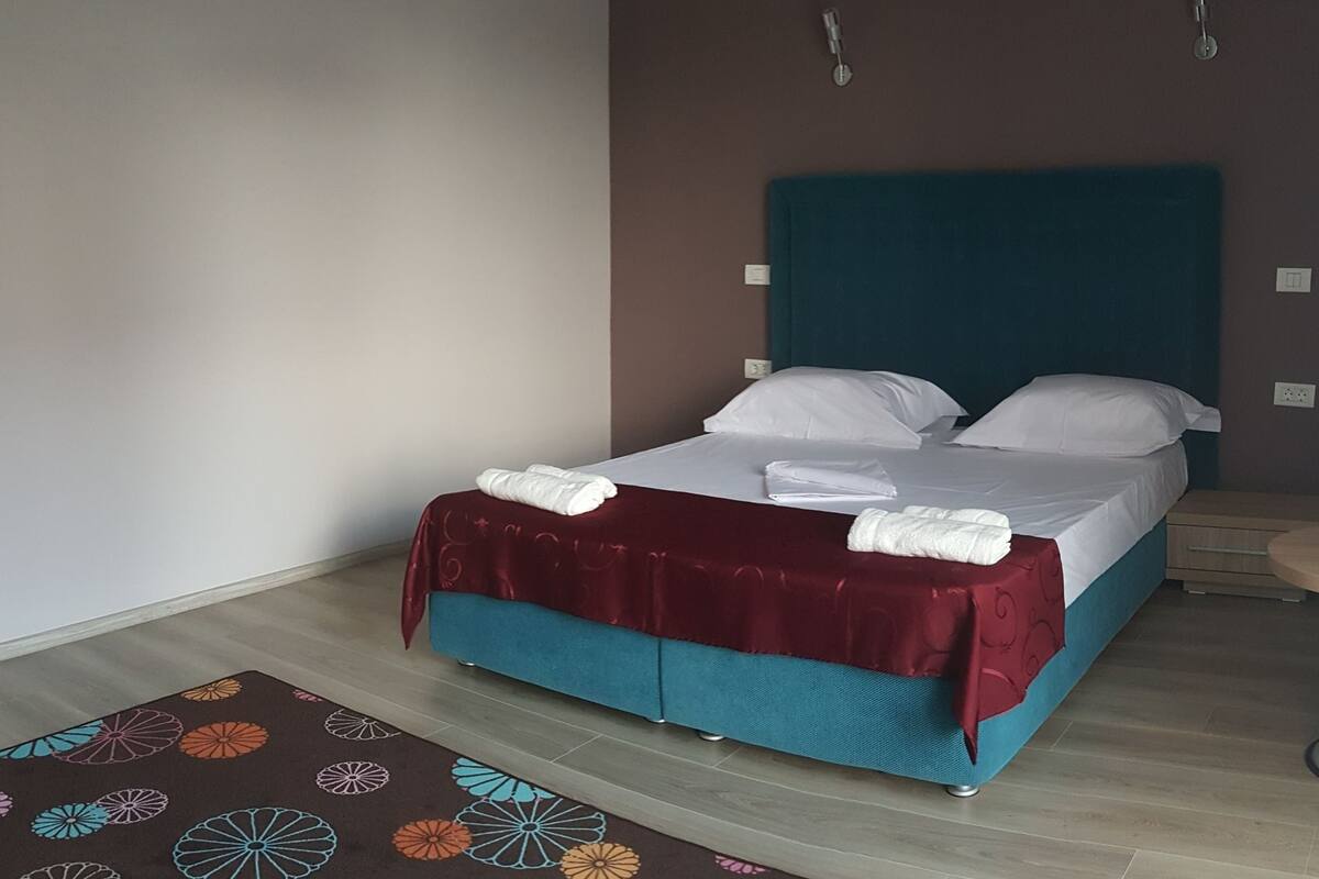 A hotel room with a bed, a small table, and a patterned rug.