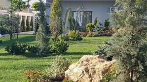 A well-maintained garden with various shrubs and a large rock in the foreground. - Sangria Luxury Family (Navodari)