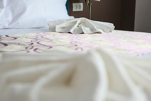 A neatly made bed with a patterned bedspread and a folded towel.