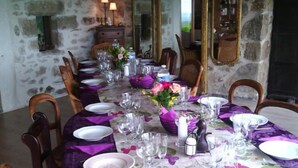 Une table à manger dressée pour six personnes, avec des nappes violettes et des centres de table floraux.
