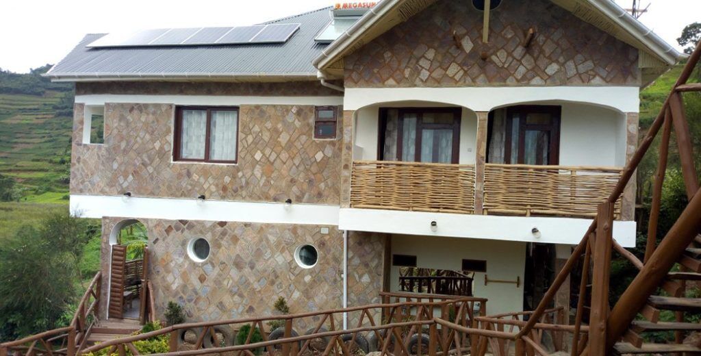 A two-story house with a stone facade, a balcony, and a staircase leading to the upper floor.