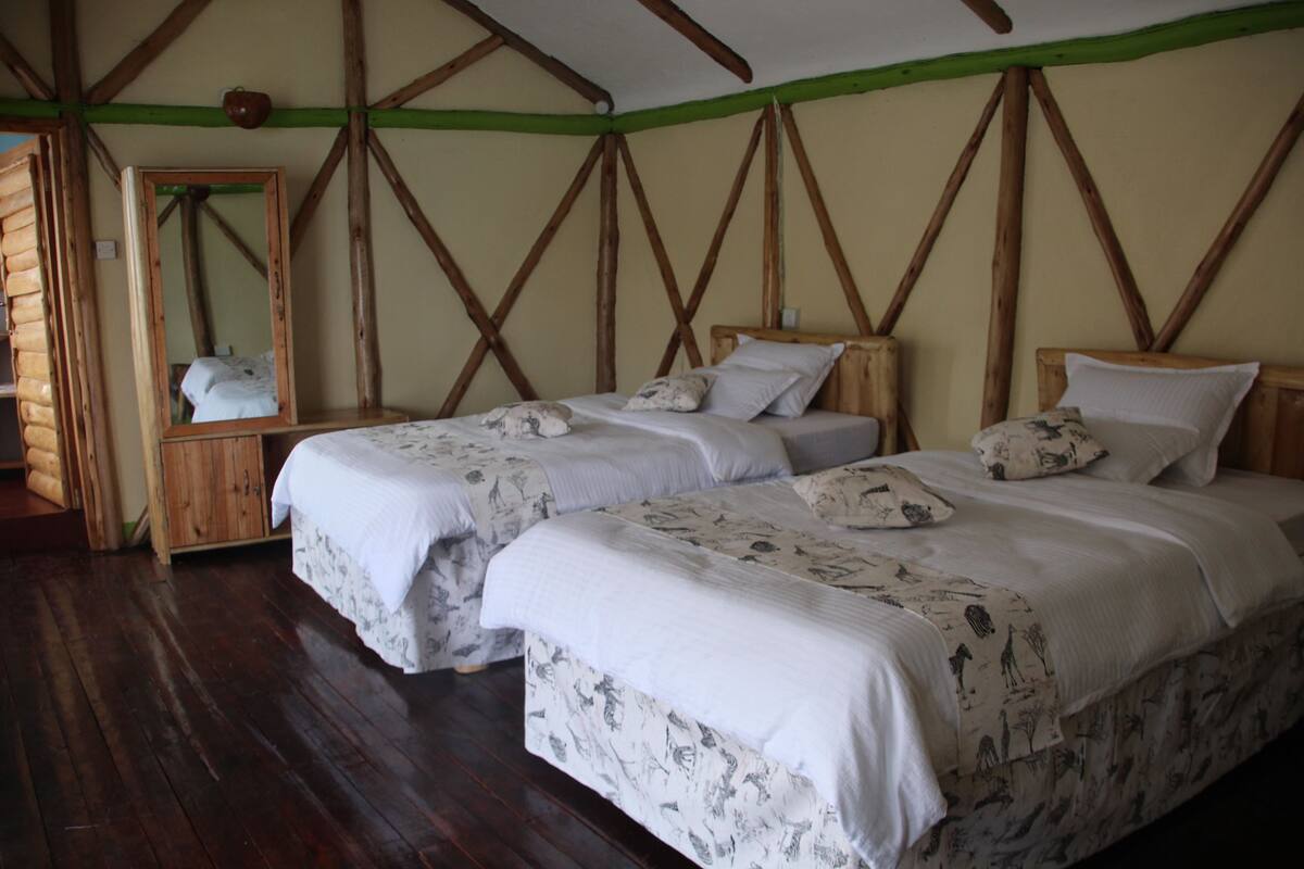 Een kamer met twee bedden, houten balken in het plafond, een houten garderobe en een spiegel.
