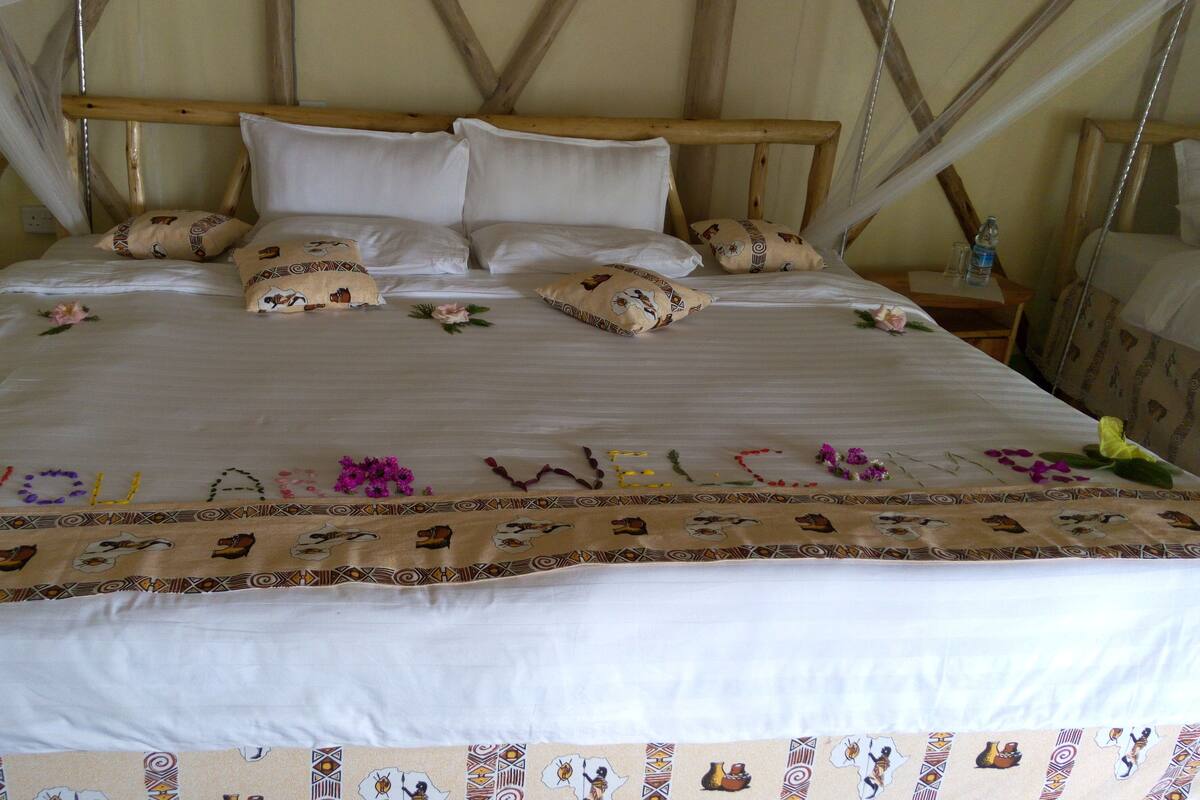 Een bed met hemelbed, kussens en een decoratieve spreidek met een welkomstbericht.