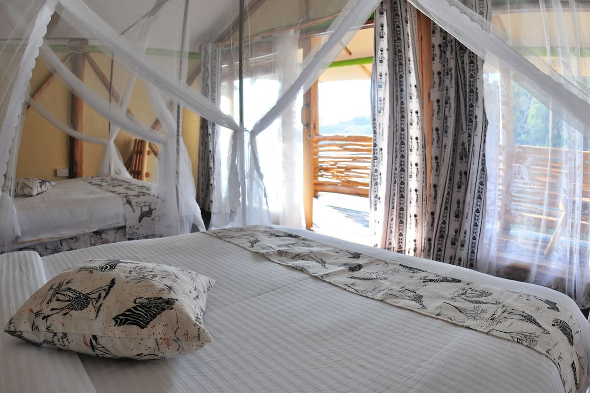 Een bed met hemelbed, gekleurde kussens en gordijnen.