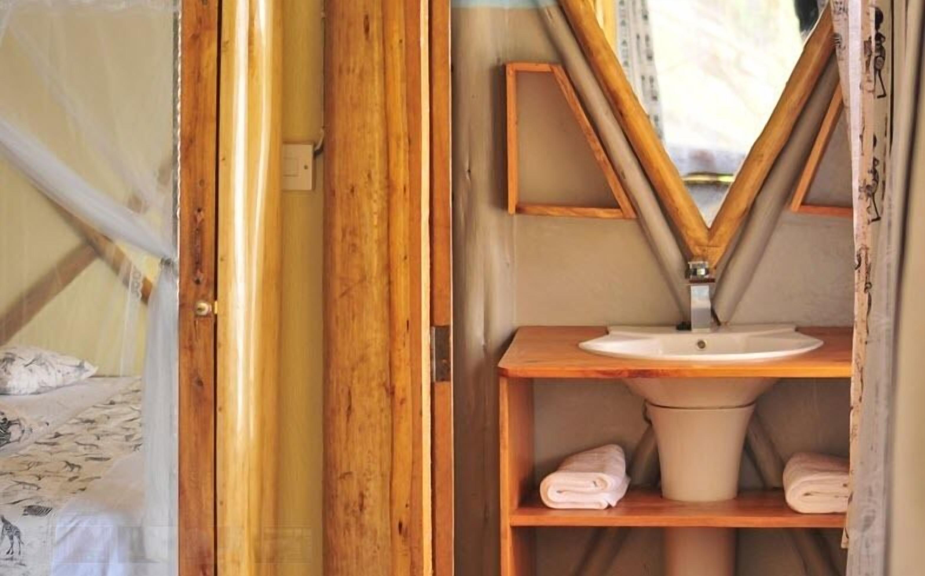 A bathroom with a wooden vanity, a sink, and a toilet. There are towels on the shelf.