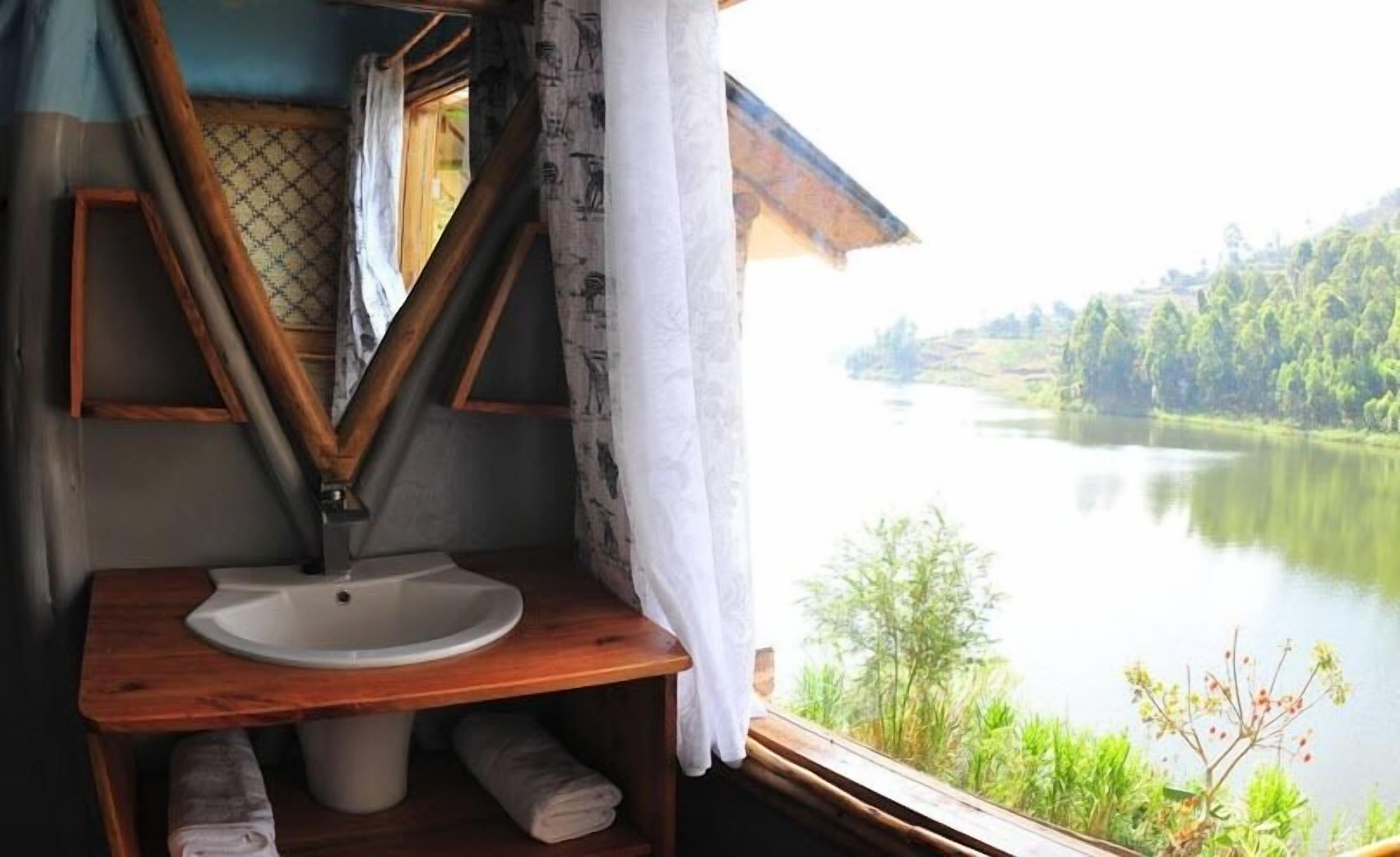 A bathroom with a wooden vanity, a sink, and a window overlooking a lake.
