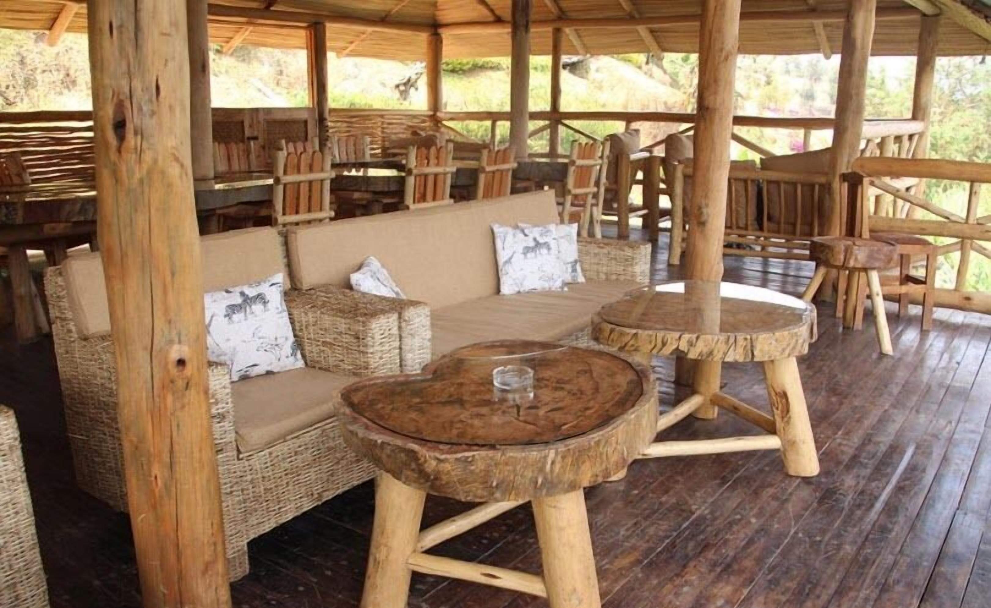 Un espace extérieur aménagé, abrité et doté de mobilier en osier et de tables en bois.