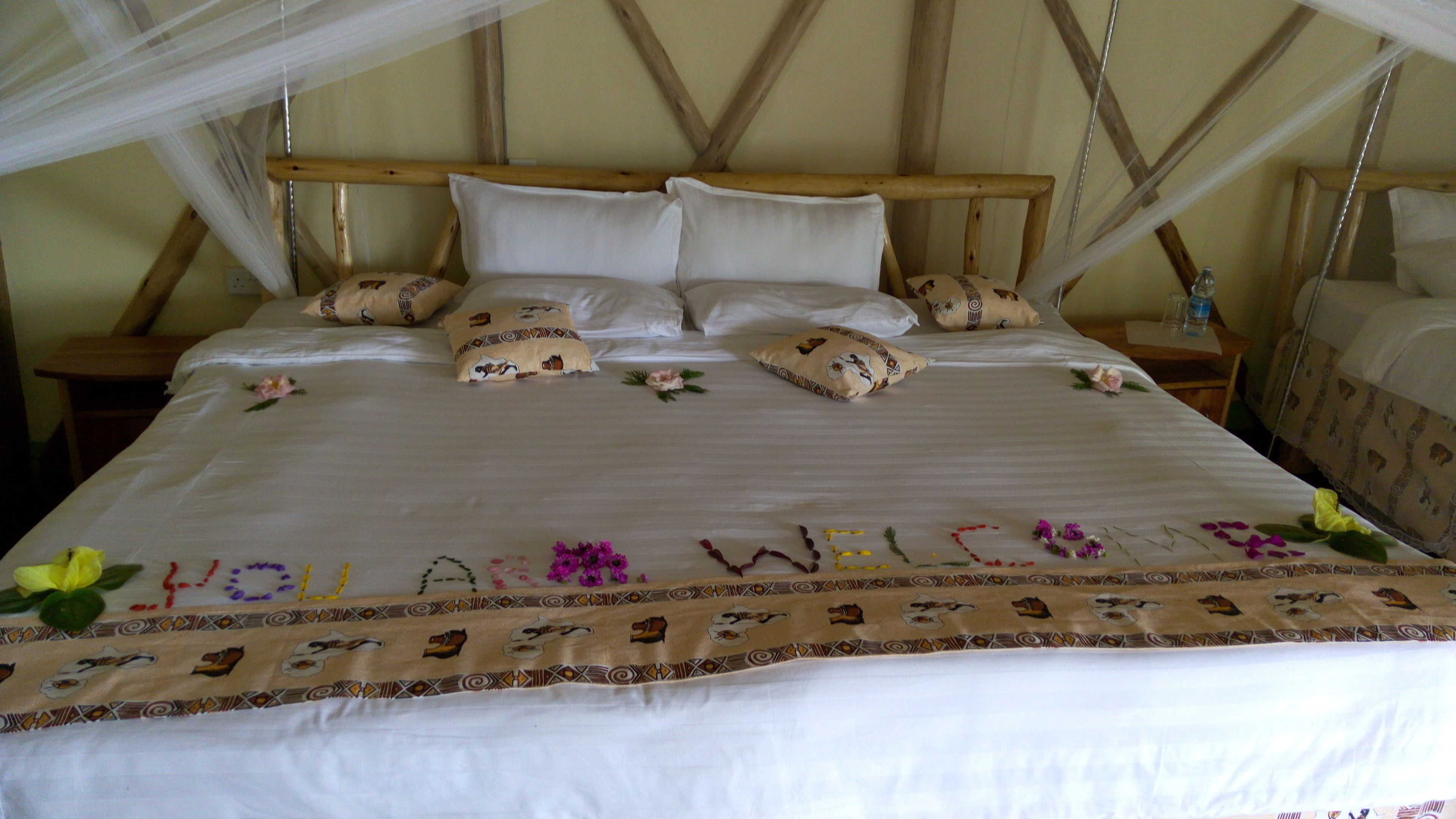 A bed with a canopy, pillows, and a decorative bedspread with a welcome message.