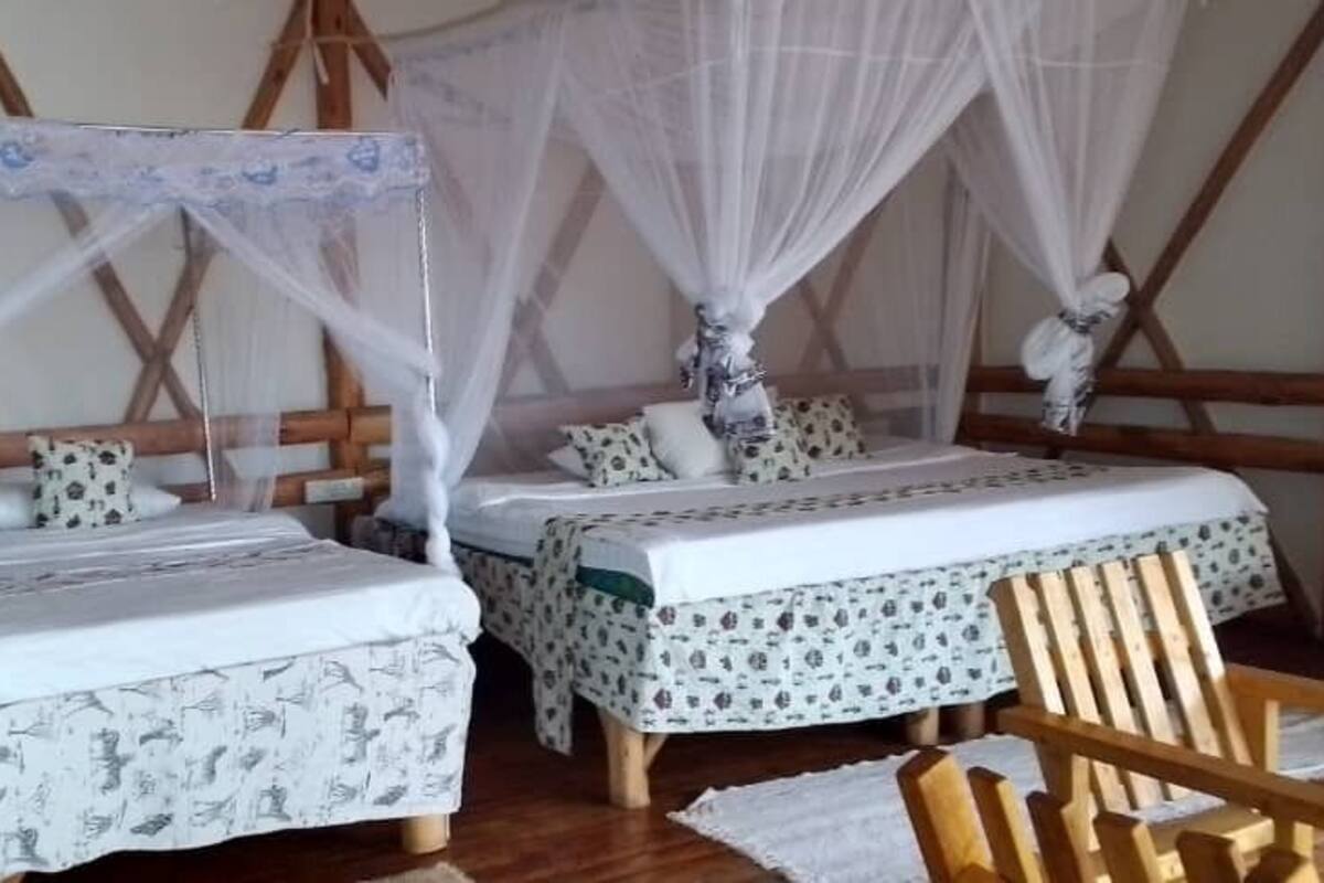 Een kamer met twee bedden, elk met een hemelbed, en een houten stoel.