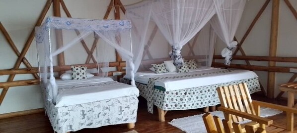 Een kamer met twee bedden, elk met een hemelbed, en een houten stoel.