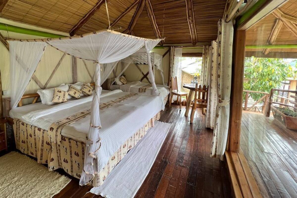 Een kamer met een bed onder een klamboe, houten meubels en uitzicht op de omgeving.