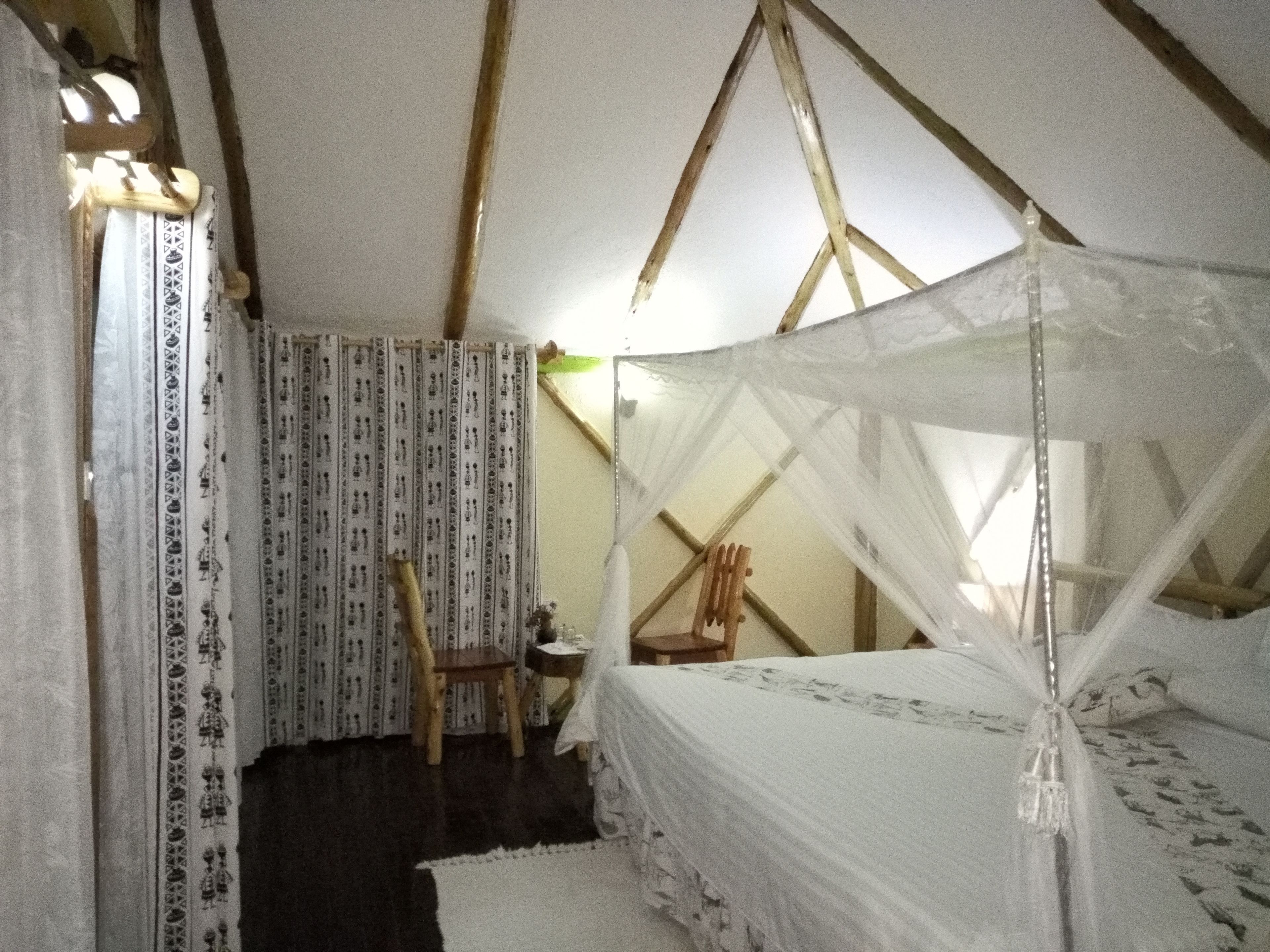 A tented room with a bed, a chair, and a small table.