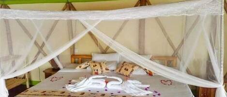A bed with a canopy, pillows, and decorative swans on the bedspread.
