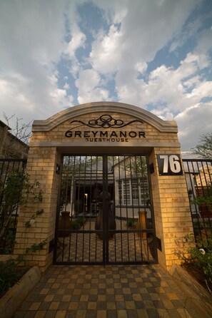 The entrance to Grey Manor Guesthouse, featuring a brick facade, a black gate, and the number 76. - Grey Manor Guesthouse (Potchefstroom)