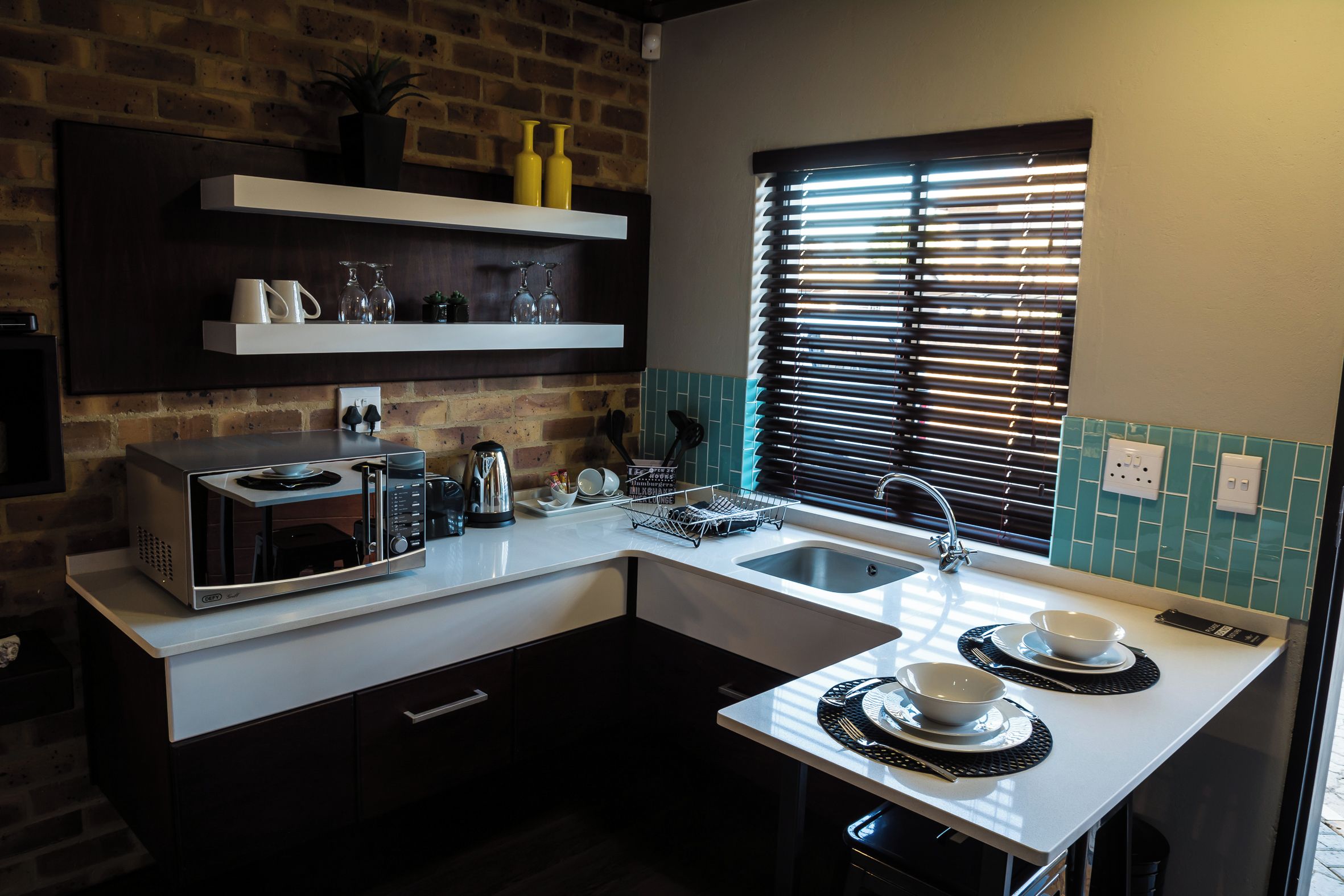 A modern kitchen with a built-in microwave, a sink, and a window with blinds.