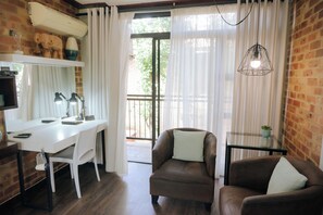 A room with a desk, two chairs, a hanging light fixture, and a view through a window with curtains. - Grey Manor Guesthouse (Potchefstroom)