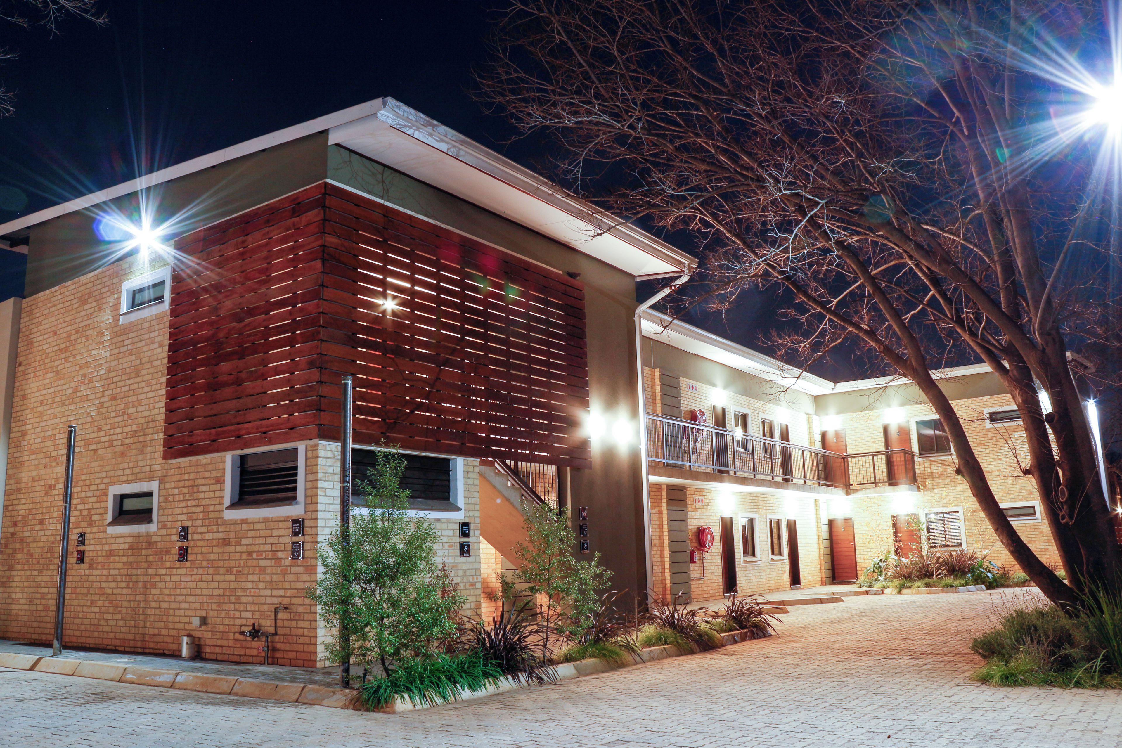A two-story building with a brick facade, a wooden slatted section on the left, and a balcony on the upper floor.