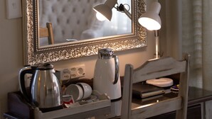 A room with a large ornate mirror, a desk with a kettle, a lamp, and a chair. - Grey Manor Guesthouse (Potchefstroom)