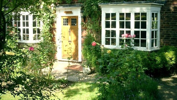 Une maison traditionnelle en briques, avec une porte en bois et une structure blanche dotée de fenêtres.