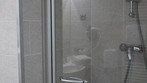 Un baño moderno con cabina de ducha de vidrio, inodoro a la vista y ducha de mano.