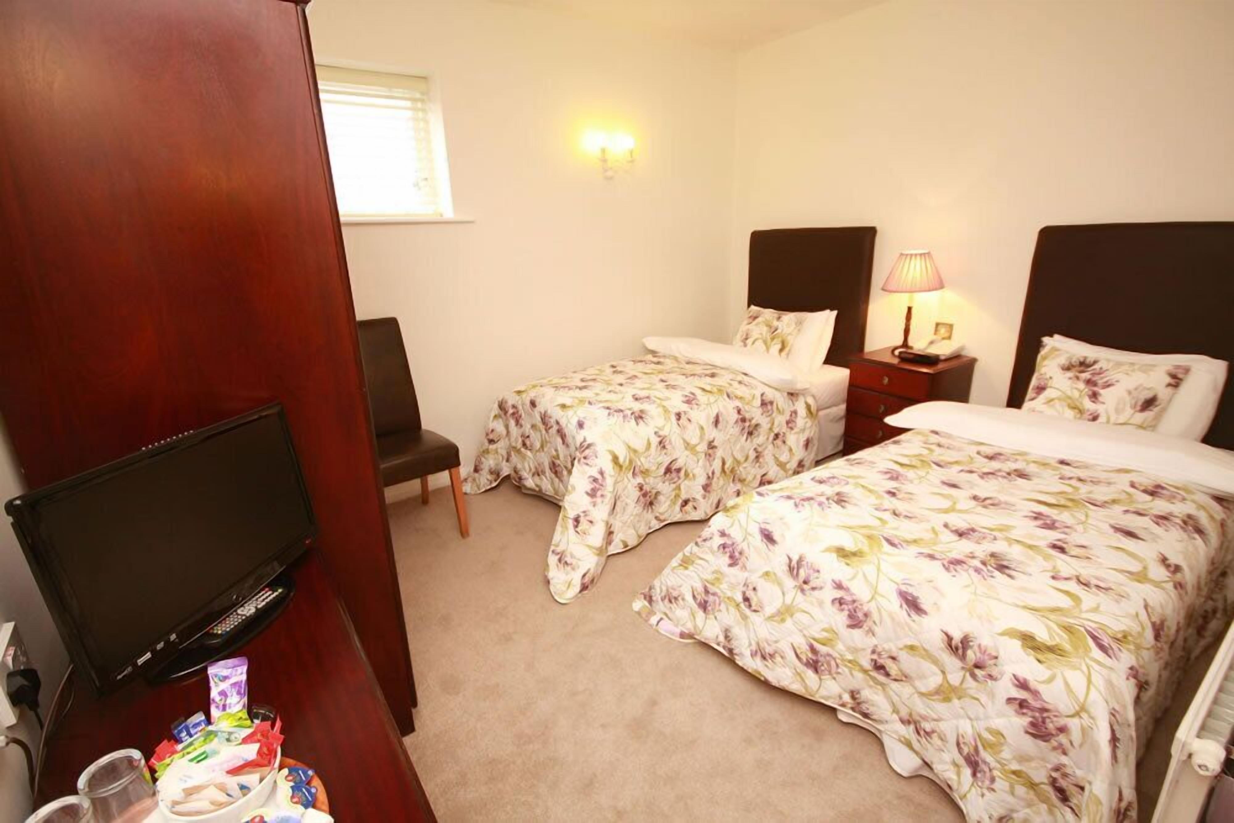 A hotel room with two beds, a TV, a desk, and a chair.