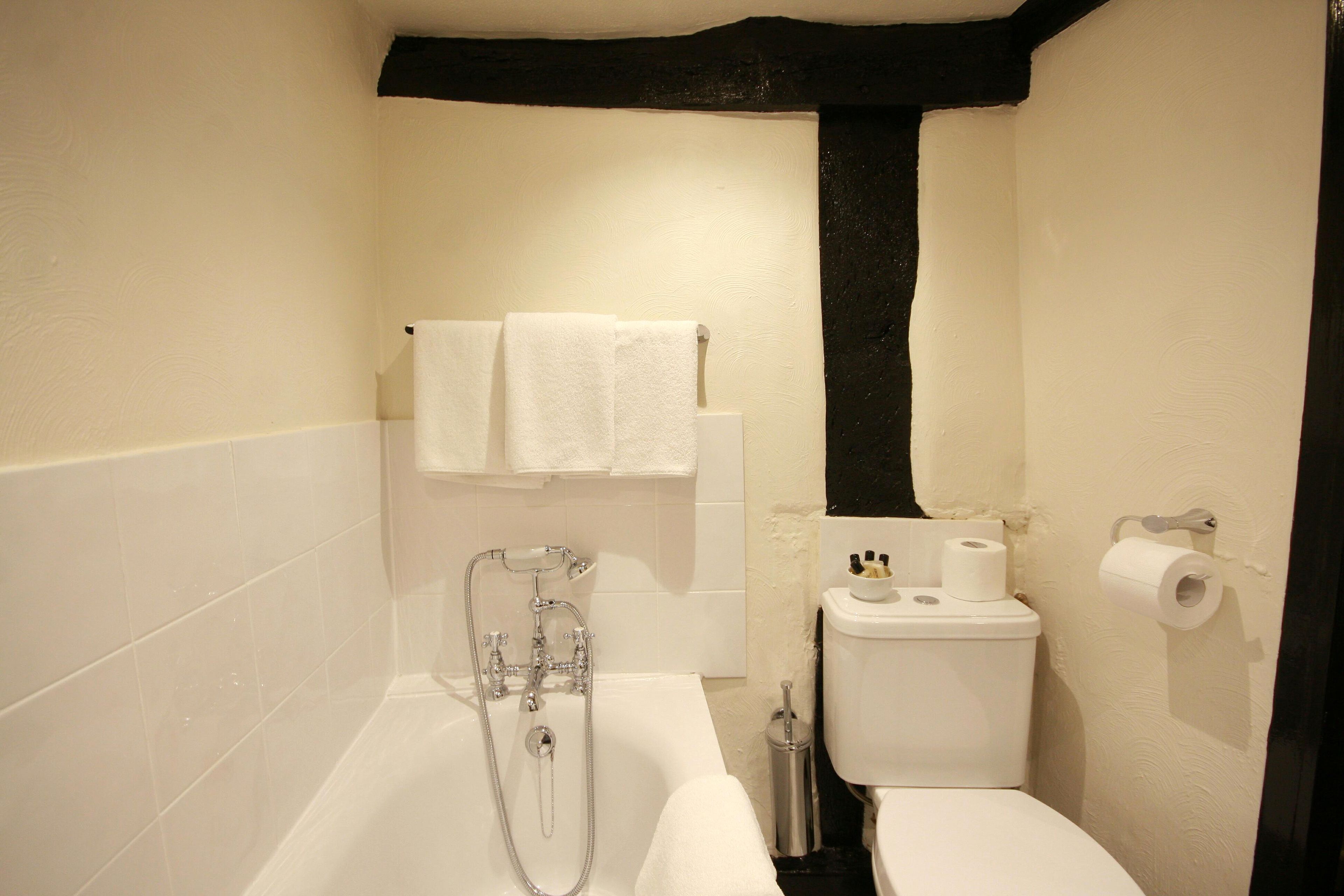 A bathroom with a bathtub, toilet, and towel rack.
