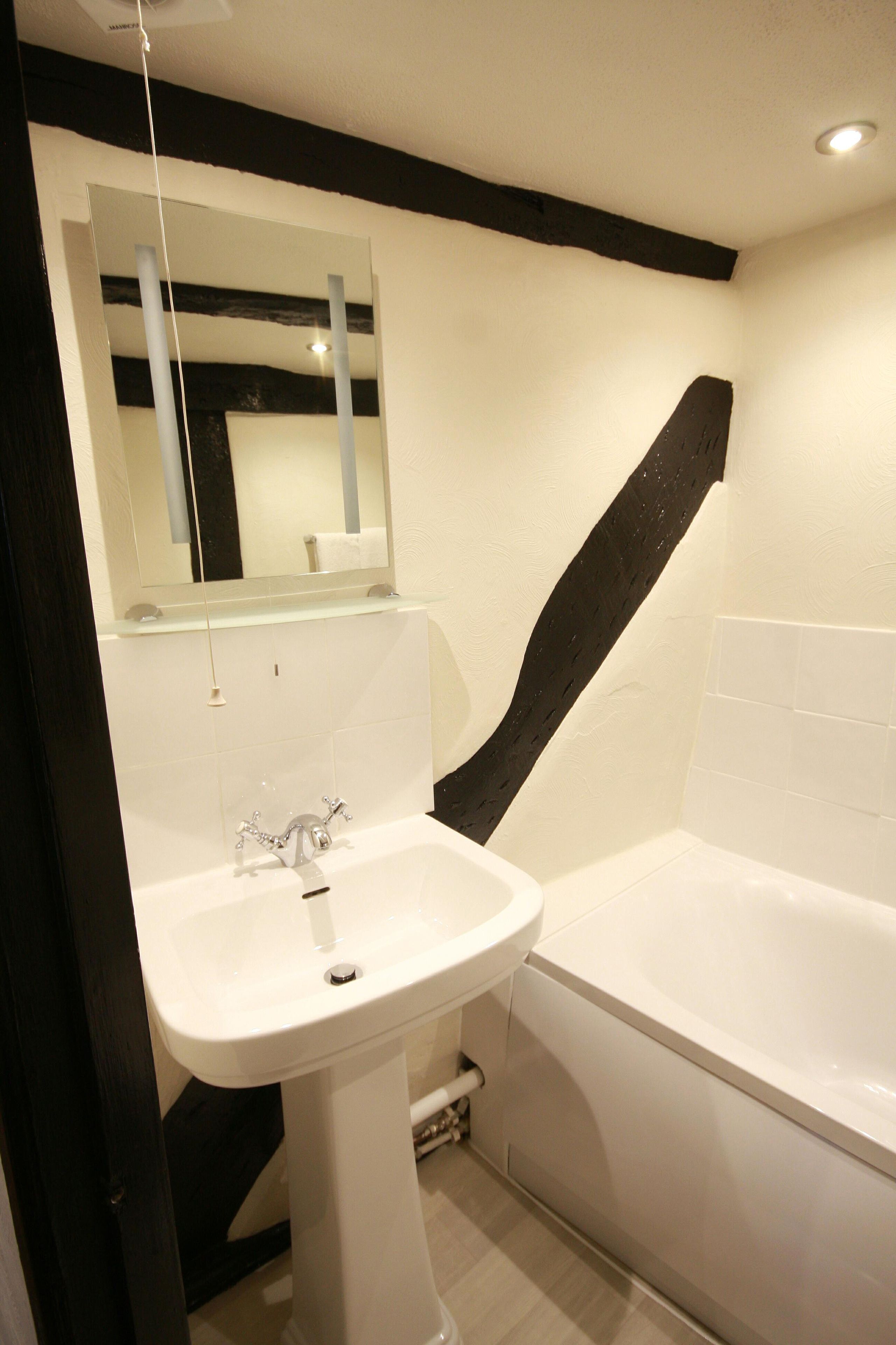 A bathroom with a white sink, a mirror, and a bathtub.