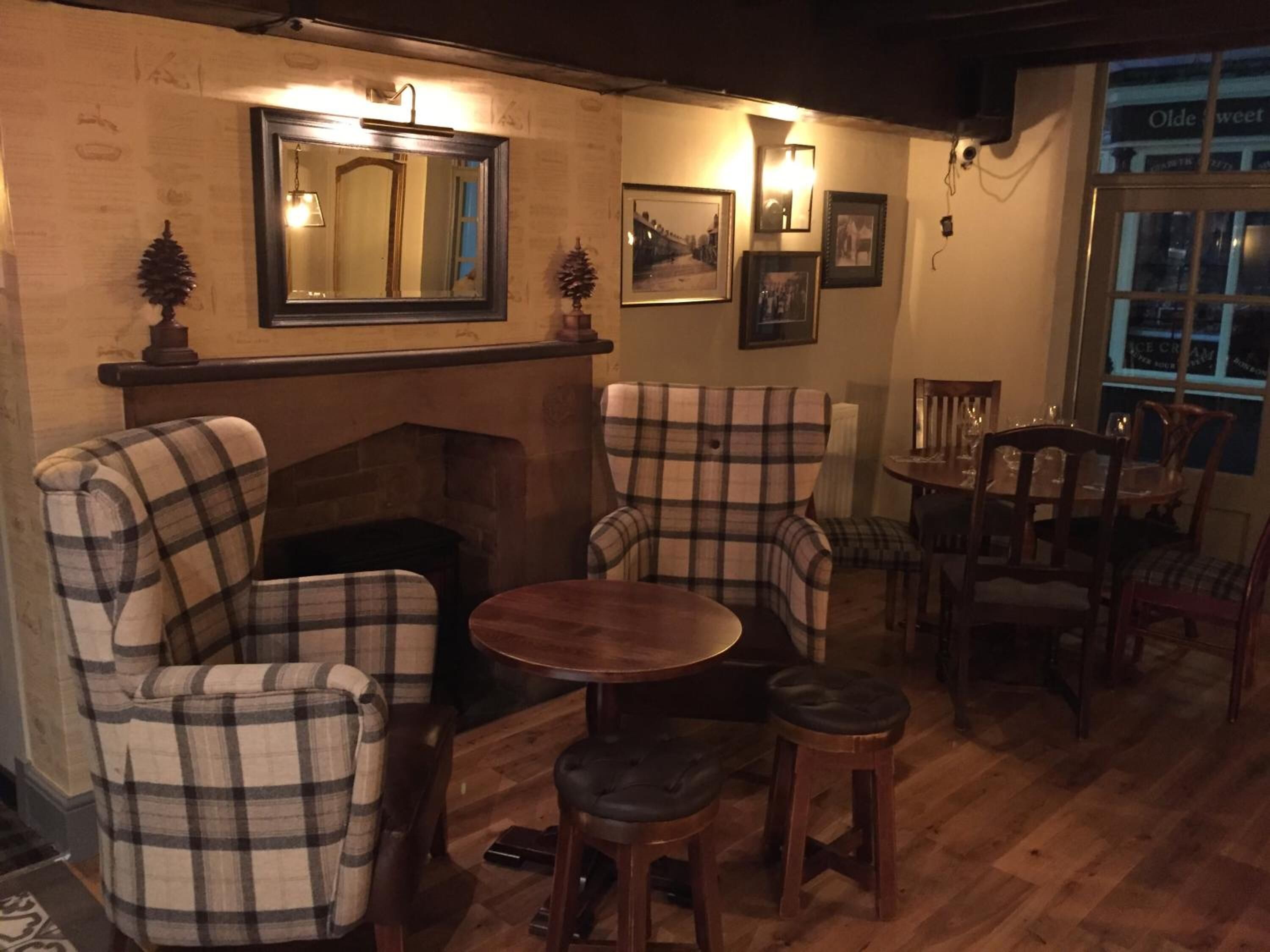 A cozy room with plaid chairs, a fireplace, and a dining area with wooden furniture.