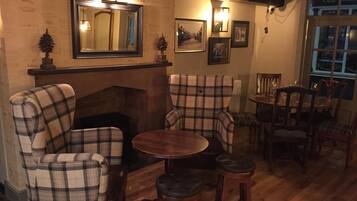 A cozy room with plaid chairs, a fireplace, and a dining area with wooden furniture.