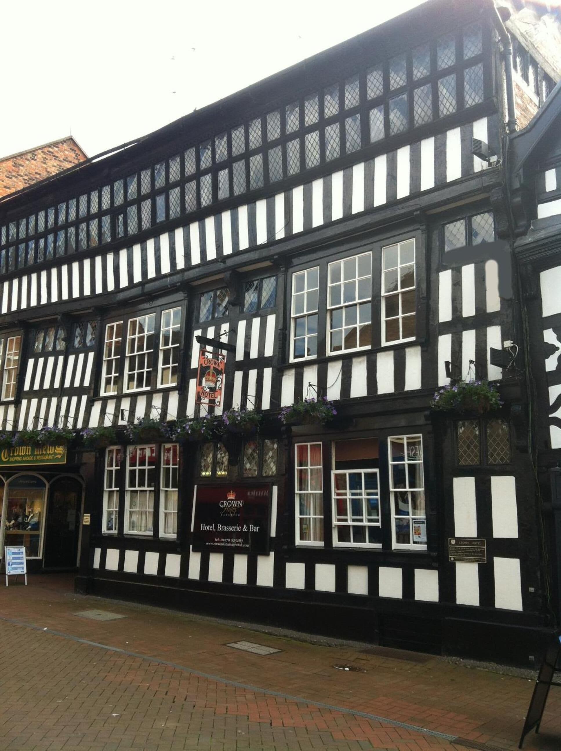 A traditional black and white half-timbered building with a sign for 'Crown Hotel, Brasserie & Bar'.
