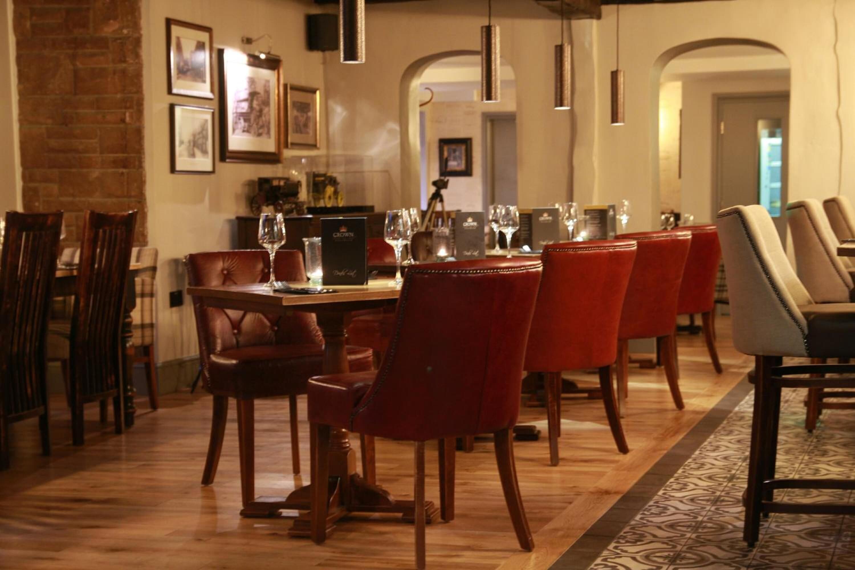 Un comedor con mesa de madera, sillas tapizadas rojas y una alfombra estampada.