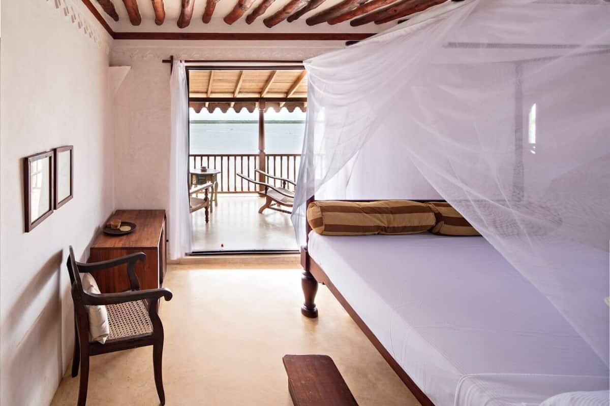 Ein Zimmer mit Bett, Schreibtisch, Stuhl und Meerblick.