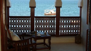 A balcony with three arches, a wooden chair, and a table.