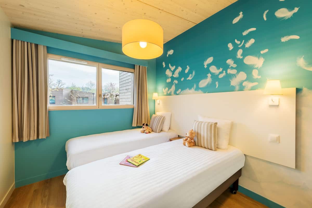 A hotel room with two beds, a large window, and a mural on the wall.
