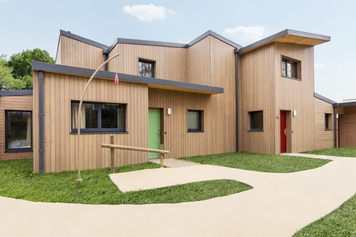 A modern building with a wooden facade, multiple windows, and a green door.