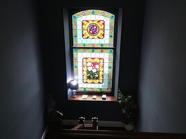 A stained glass window with floral patterns and a shield emblem.