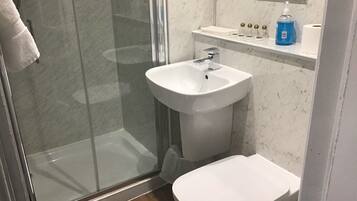 A bathroom with a glass shower enclosure, a white sink with a mirror above it, and a toilet.