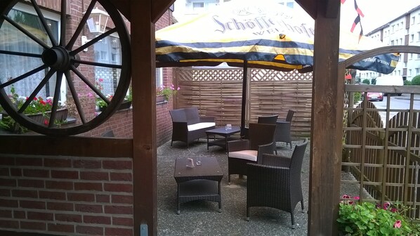 An outdoor seating area with wicker furniture and a large umbrella.