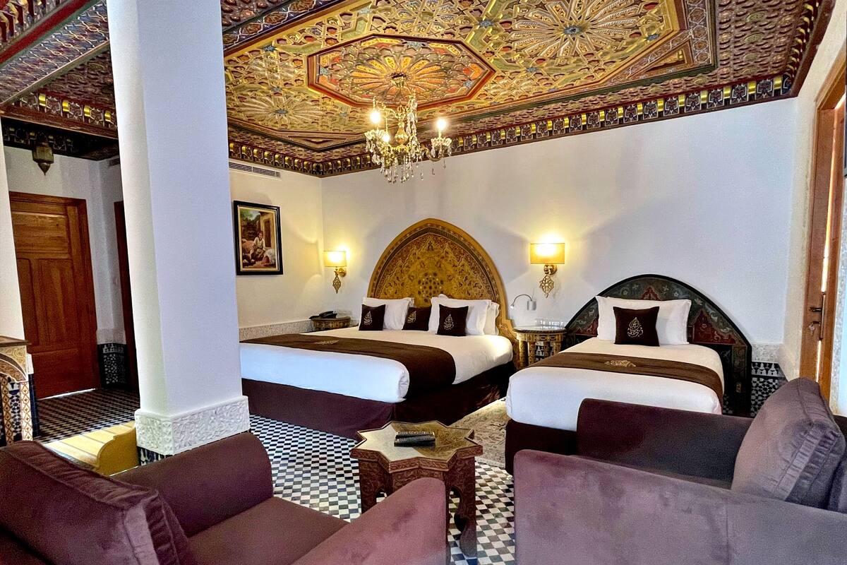 A hotel room with two beds, a chandelier, and a checkered floor.