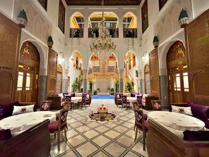 A luxurious hotel lobby with ornate arches, a central fountain, and a high ceiling with chandeliers. - Riad Marjana Suites & Spa (Fes)