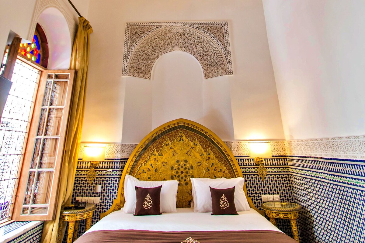 Una habitación con una cama grande, techo ornamentado y paredes con diseños.