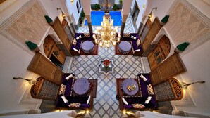 A luxurious interior with a central chandelier, ornate walls, and a pool visible through an archway. - Riad Marjana Suites & Spa (Fes)