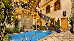 An indoor swimming pool with a tiled floor and a staircase with ornate railings. - Riad Marjana Suites & Spa (Fes)
