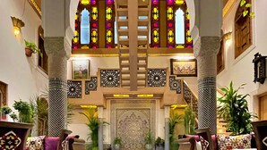 A luxurious lobby with a central fountain surrounded by rose petals, ornate columns, and a view of a grand staircase. - Riad Marjana Suites & Spa (Fes)