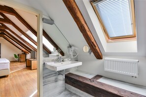 A modern bathroom with a skylight, a white sink, and a wooden bench. - Hotel Garden Court (Prague)