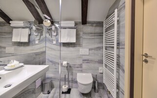 Casa de banho moderna com painel de fundo de mármore, uma sanita branca, uma pia e zona de duche.