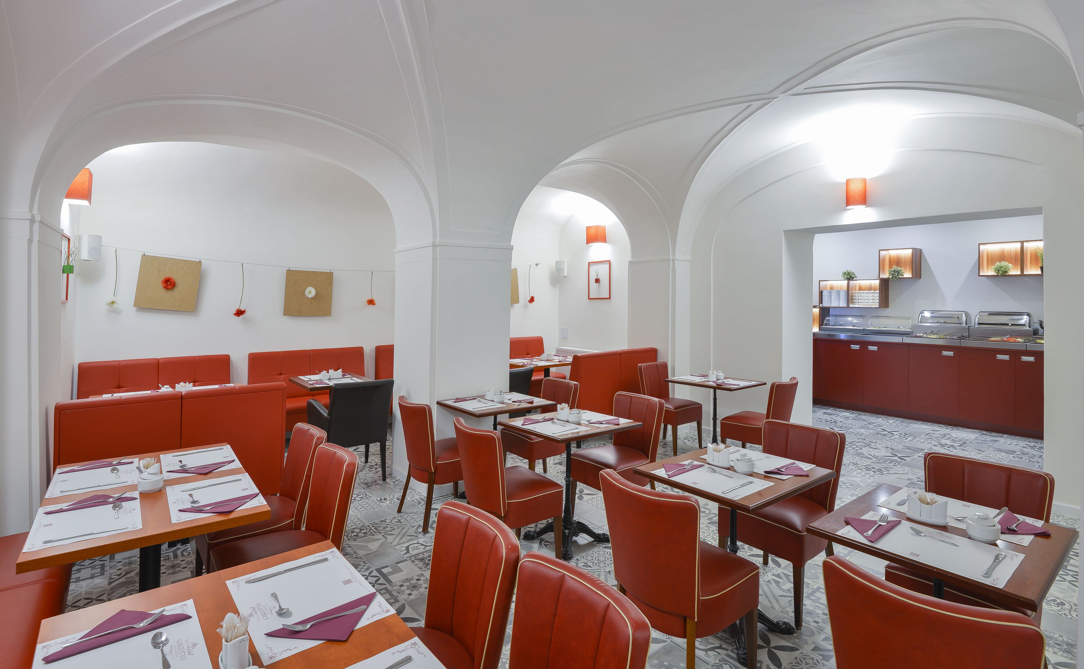 A restaurant with red booths and tables, white walls, and a buffet area.