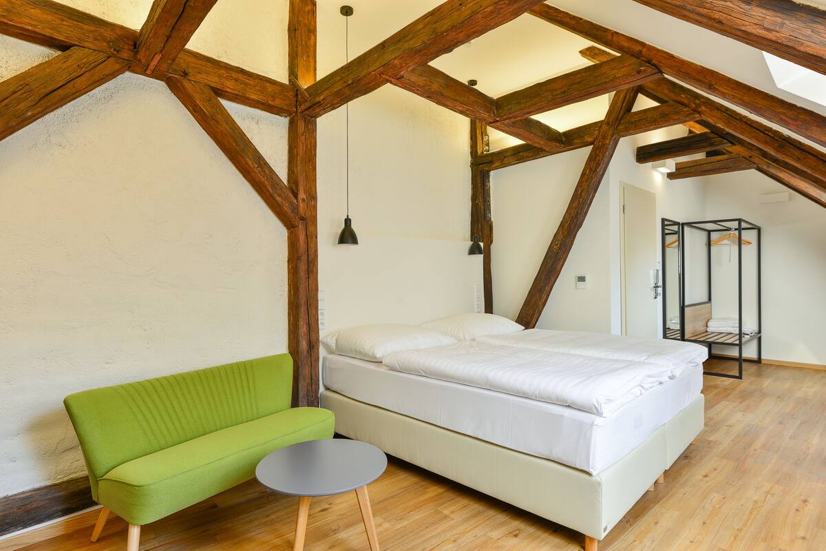 A bedroom with a bed, a green sofa, and a small table.