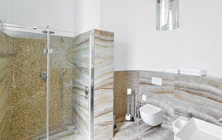 Un bagno moderno con cabina doccia in vetro, un water e un lavandino.